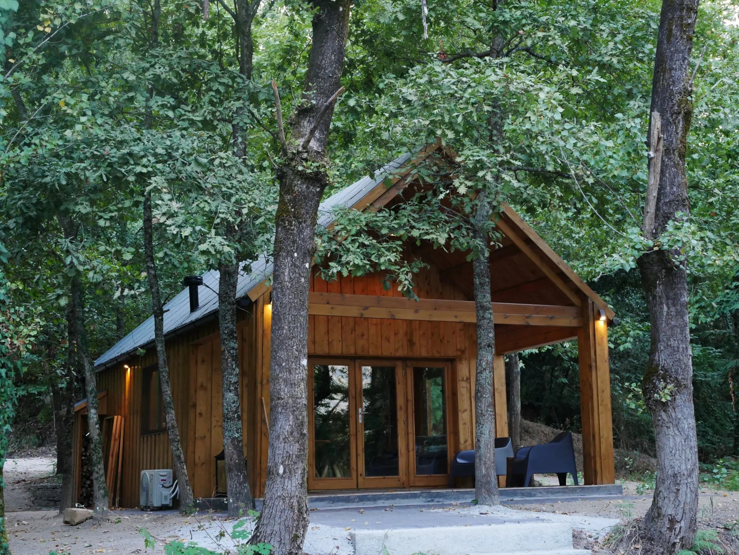 Cabana das Aveleiras entre as árvores, com o alpendre iluminado